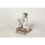 LLADRO PORCELAIN ORIENTAL FEMALE FIGURE, painted in colours and modelled kneeling in front of a vase