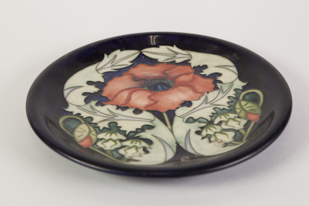 MODERN MOORCROFT TUBE LINED POTTERY PLAQUE POPPY FLOWER, BUDS AND LEAVES on a dark blue ground,