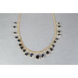 AN EDWARDIAN GOLD COLOURED METAL NECKLACE, suspending twenty one collet set cabochon stones of