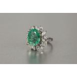 *18ct WHITE GOLD, EMERALD AND DIAMOND CLUSTER RING set with a centre oval emerald, approximately 14.