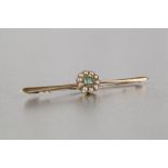 AN EDWARDIAN 15ct GOLD BAR BROOCH, set centrally with a green stone within a surround of tiny seed