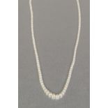 SINGLE STRAND NECKLACE OF GRADUATED NATURAL SALTWATER PEARLS with white metal torpedo shaped