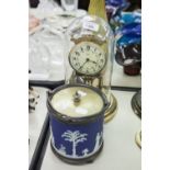 AN ANNIVERSARY CLOCK UNDER PLASTIC DOME AND A WEDGWOOD BISCUIT BARREL WITH ELECTROPLATE SWING HANDLE