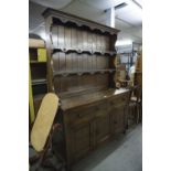 A REPRODUCTION OAK DRESSER, THE RAISED BACK WITH TWO SHELVES, THE BASE WITH TWO DRAWERS AND THREE