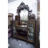 A CARVED MAHOGANY 'SIDE BY SIDE' DISPLAY CABINET WITH SHAPED ORNATE MIRROR BACK, RAISED ON