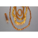 NECKLACE OF GOLDEN CHIP AMBER PIECES, TWO AMBER COLOURED BEAD NECKLACES, a bracelet and an amber