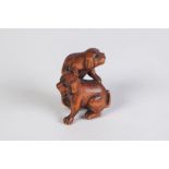 A JAPANESE WELL CARVED BOXWOOD NETSUKE, of two puppies at play with a ball, with glass inset eyes,