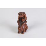 A JAPANESE WELL CARVED BOXWOOD NETSUKE OF A MONKEY HOLDING A FRUIT standing on the back of a rabbit,