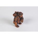 A JAPANESE WELL CARVED BOXWOOD NETSUKE OF A MONKEY HOLDING A FRUIT in its right hand, further fruits
