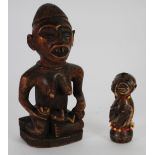 YOMBE CARVED WOOD MATERNITY FIGURE, modelled seated with a baby and bottle, on an oval base, 9" (