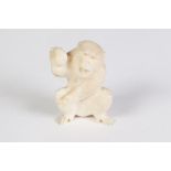 A SMALL JAPANESE CARVED IVORY MODEL OF A SEATED MONKEY holding a nut in the throws of breaking it