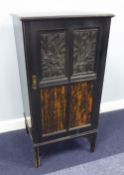 AN EDWARDIAN EBONISED MUSIC CABINET WITH FRAMED EMBOSSED AND COROMANDEL WOOD PANELS, ON SQUARE