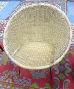 A CIRCULAR WICKER CHAIR ON BLACK METAL WIRE PATTERN SUPPORTS