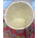 A CIRCULAR WICKER CHAIR ON BLACK METAL WIRE PATTERN SUPPORTS