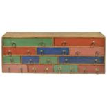 A colourful rustic bank of wooden drawers, 20th century of rectangular form with thirteen drawers of