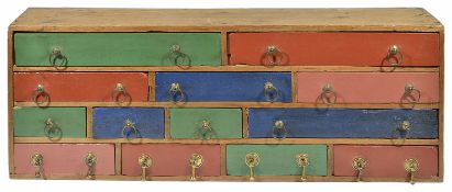 A colourful rustic bank of wooden drawers, 20th century of rectangular form with thirteen drawers of