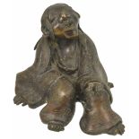 A 19th century Japanese bronze figure of a seated Lohan the figure leaning back on one hand with