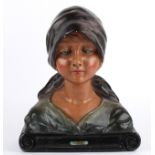 A French Art Deco bust of a female, 1930's wearing a headscarf, and shawl, upon a scroll incised