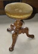 A Victorian walnut piano stool, the upholstered circular seat above bulbous support with three s-