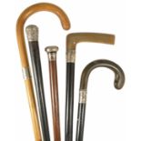 A collection of five walking sticks to include two ebonised horn handed walking sticks with silver