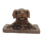 A dogs head inkwell desk stand, 20th century modelled as a dogs head and paws resting upon a plank
