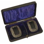 A cased set of early 19th cut steel and leather buckles of oval form with cut steel border and