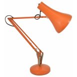 A retro orange angle poise desk lamp with weighted circular base and adjustable arm height