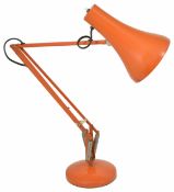 A retro orange angle poise desk lamp with weighted circular base and adjustable arm height