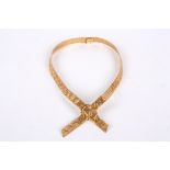 A Continental .750 gold articulated mesh 'tie' necklace formed as crossed, textured ribbons fastened