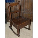 An oak child's rocking chair, 19th century the slatted back above panelled seat with a side drawer
