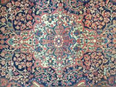 An early 20th century Persian carpet, possibly Kashan the quartered indigo field with central floral