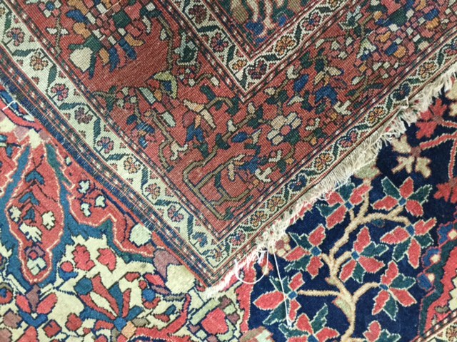 An early 20th century Persian carpet, possibly Kashan the quartered indigo field with central floral - Image 4 of 6
