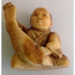 A small ivory Japanese okimono figure the realistically carved figure of seated gentleman holding