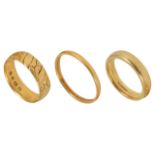 A 22ct gold wedding band and two 18ct gold wedding bands, one with engraved decoration (3) 22ct