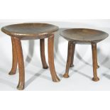 Two 20th century African tribal stools, each with dished seats upon four supports, together with a