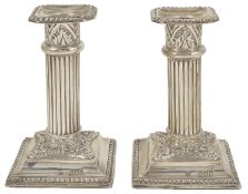 A pair of Victorian silver dwarf candlesticks, London 1897 the bead edge drip trays above fluted