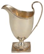 A George III silver cream jug, London 1790 of helmet form with ribbed handle upon a square