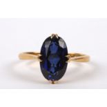 A simple 22ct gold mounted synthetic sapphire set ring the oval stone of pleasing colour, in