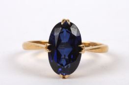 A simple 22ct gold mounted synthetic sapphire set ring the oval stone of pleasing colour, in