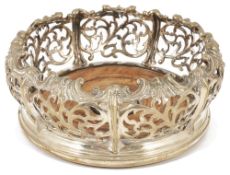 A circular silver plated wine bottle coaster, with pierced strapwork scrolled gallery rail above