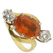 A mandarin garnet and two stone diamond set cocktail ring, circa 1960the oval orange garnet set at a