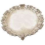 An Edwardian Mappin & Webb silver salver, London 1908with pie crust stepped border upon three ball