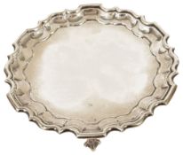 An Edwardian Mappin & Webb silver salver, London 1908with pie crust stepped border upon three ball