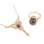 An Edwardian Arts & Crafts rose gold garnet and pearl pendant necklacethe 9ct gold scroll pendant