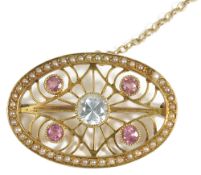 A delicate Edwardian 15ct. gold seed pearl and gem set scroll brooch,the oval brooch set with four