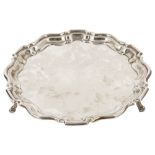 An Edwardian silver salver, London 1904with pie crust stepped edge raised upon three scrolled