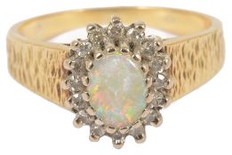 An 18ct gold opal and diamond set cluster ringthe oval opal within a border of small diamonds and