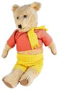 A vintage Rupert teddy bear dressed in a red top, with yellow and black checkered trousers and