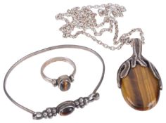 Three pieces of modernist silver and tigers eye jewellerycomprising an oval pendant on chain, a