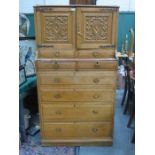 CARVED LIGHT OAK FLIGHT OF EIGHT DRAWERS WITH TWO SMALL CUPBOARD DOORS ABOVE